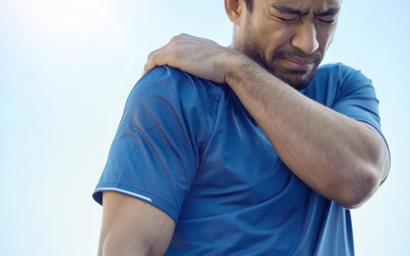 Man holding his shoulder in pain while working out outdoors in Centennial CO