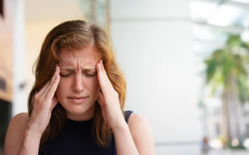 Office worker holding their head from a migraine before chiropractic care in Centennial CO
