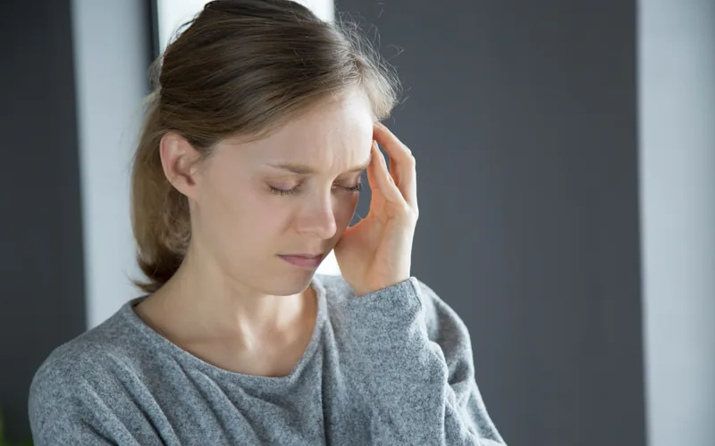 Woman holding her head feeling dizziness and vertigo, treated at Axis Health and Wellness in Centennial CO