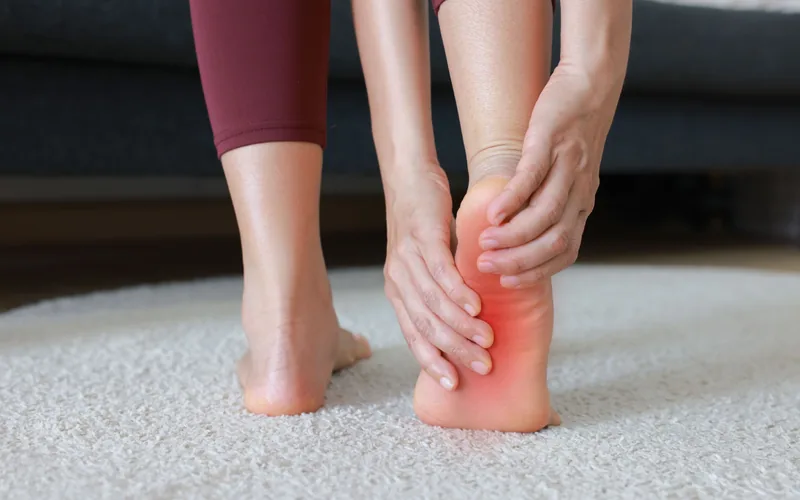 Woman massaging her heel and foot from plantar fasciitis pain in Centennial CO
