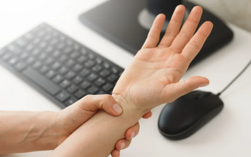 Woman holding her hand and wrist with carpal tunnel syndrome symptoms in Centennial CO